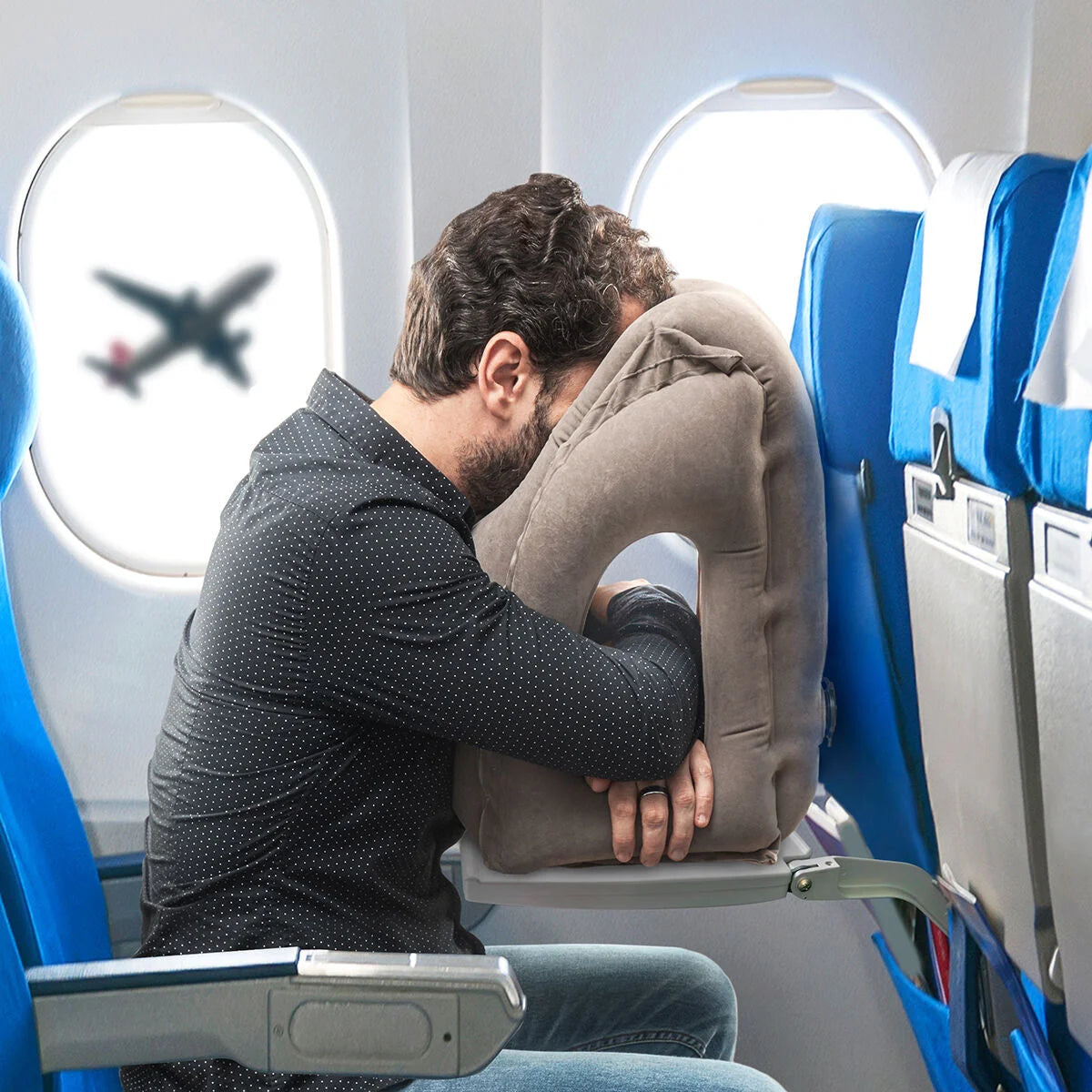 Mann nutzt das Snoozy Reisekissen frontal im Flugzeug