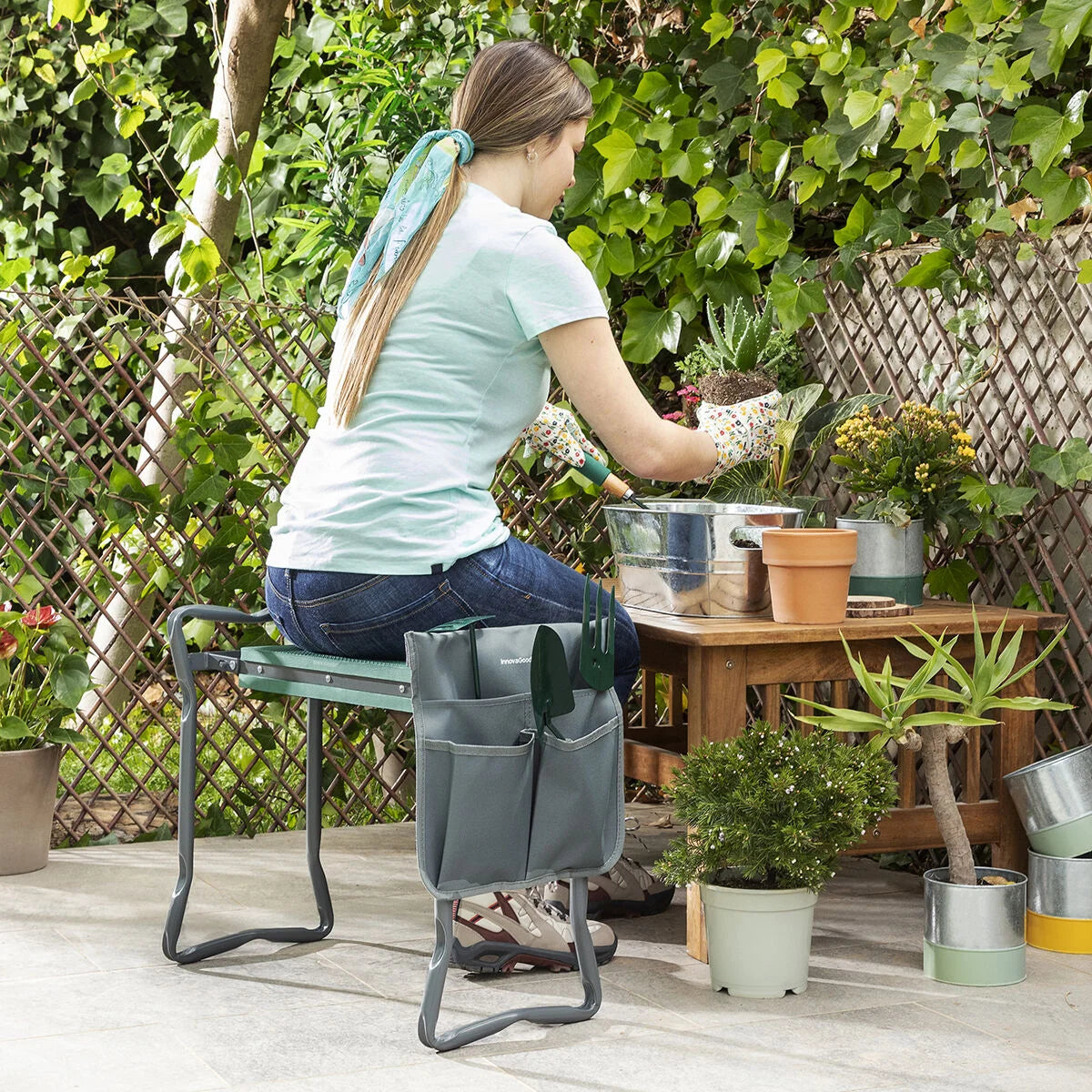 Frau arbeitet auf der Situl Garten-Kniebank an einem Pflanztisch